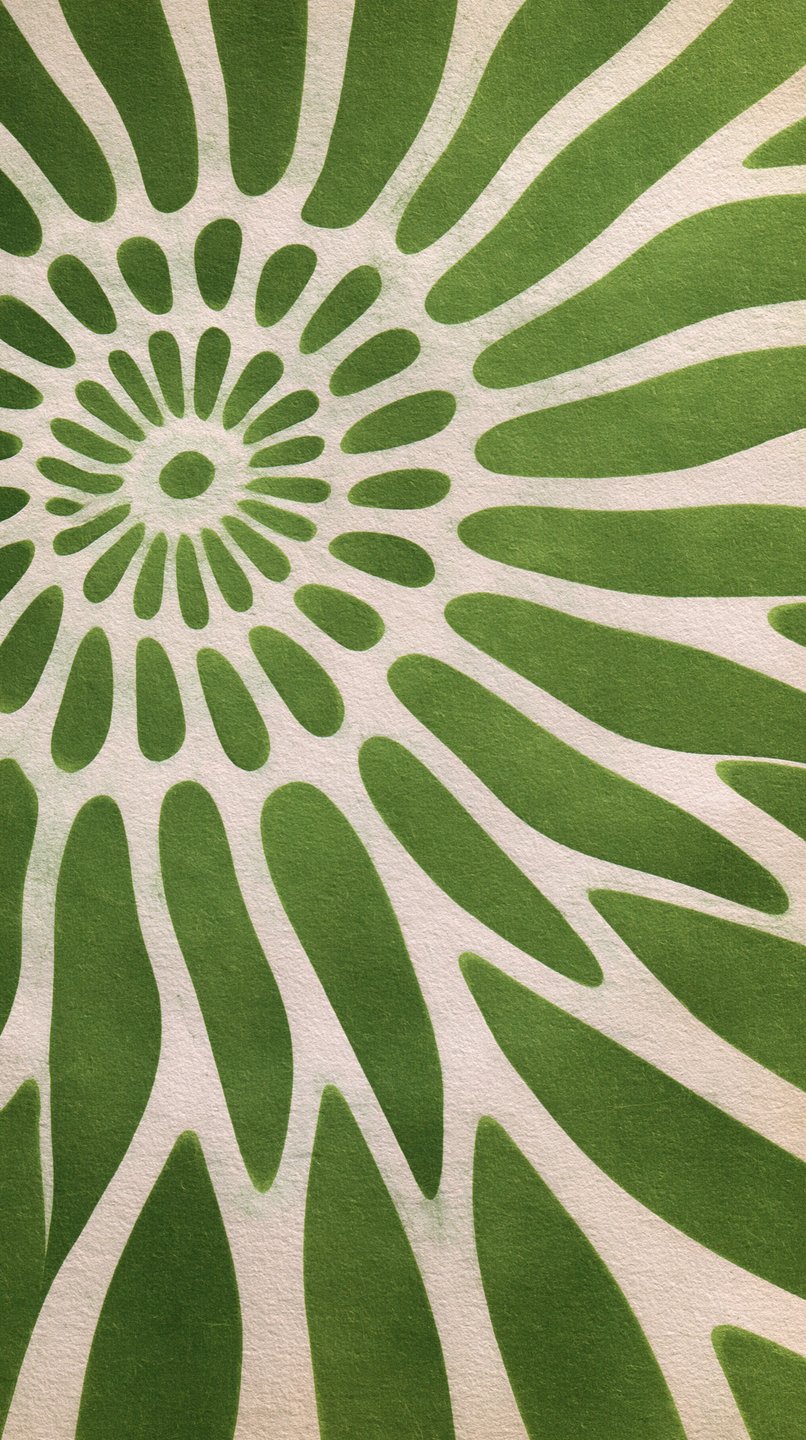 Green radiating floral sunburst pattern painted on a textured off-white plaster wall surface.