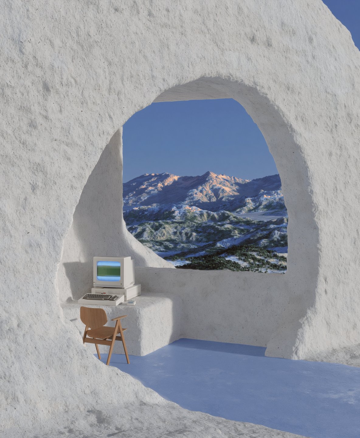 Retro computer workstation inside a white textured cave opening to a vast snowy mountain range under blue skies.