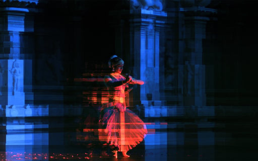 A classical Indian dancer performing in a temple with red and blue long-exposure motion blur effects.