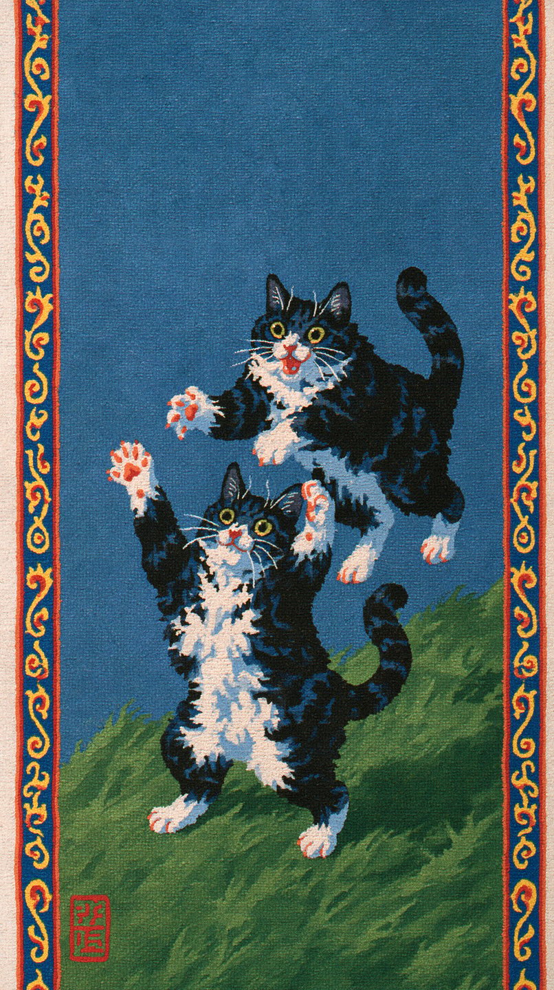 Two playful black and white tuxedo cats leap and rear on a green grassy hill within decorative borders.