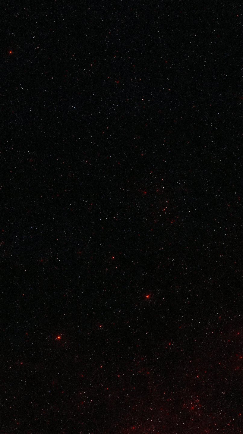 A dense field of tiny white and red stars scattered across a pitch-black deep space background.
