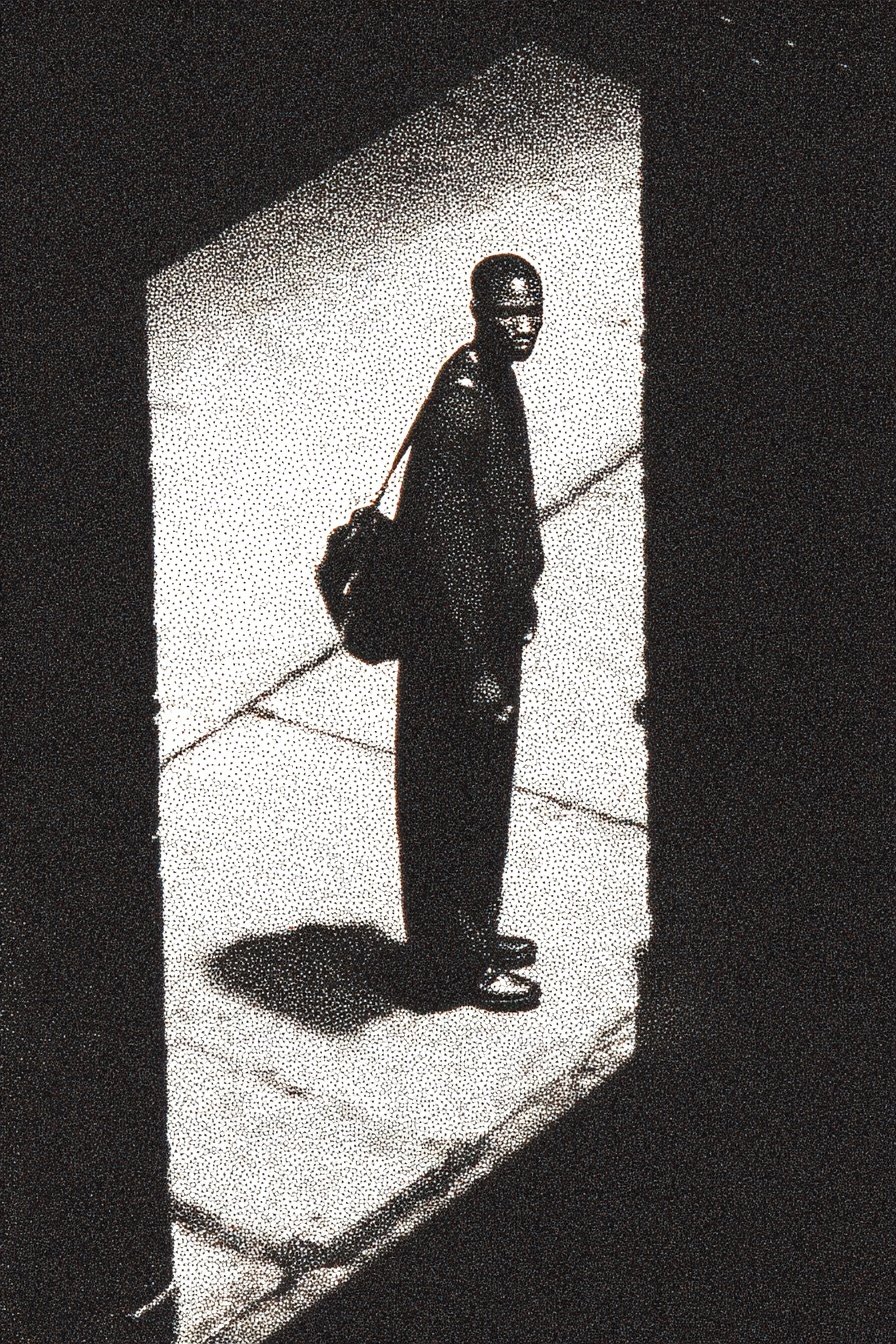 Silhouetted man with a backpack stands in a bright rectangular doorway surrounded by deep, grainy black shadows.