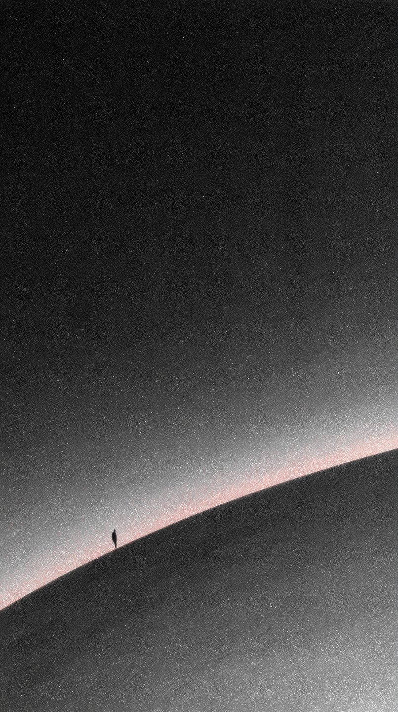 A tiny silhouette of a person stands on a curved ridge under a vast, grainy starry sky.