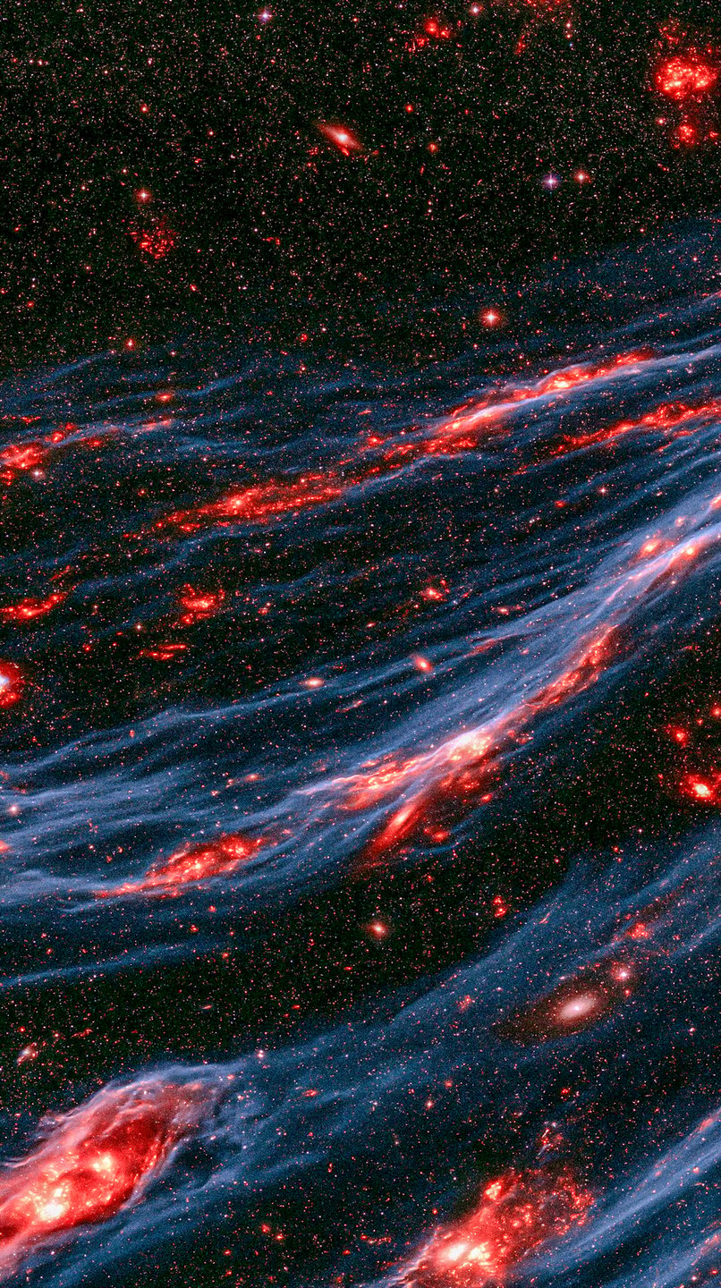 Glowing red cosmic nebula filaments flow diagonally through blue dust fields and dense background starscapes.