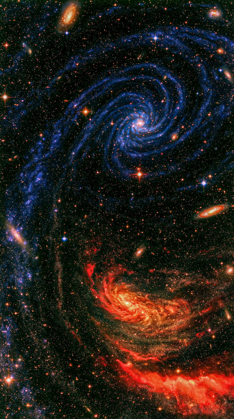 Vibrant blue spiral galaxy contrasting with a glowing red cosmic nebula across dense starfield.
