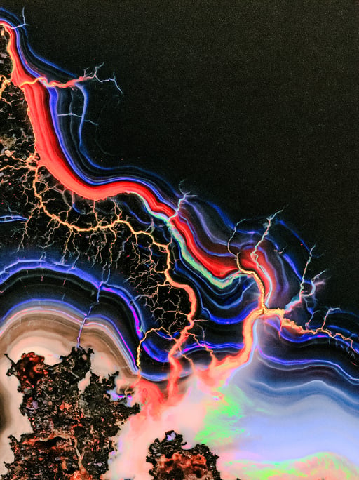 Vivid red and blue plasma arcs branch across dark obsidian with iridescent mineral banding.